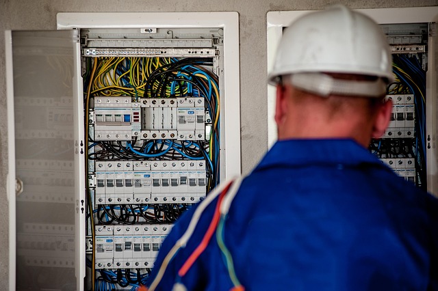 A mechanic working on an electric car battery pack, with specialized tools and safety equipment.