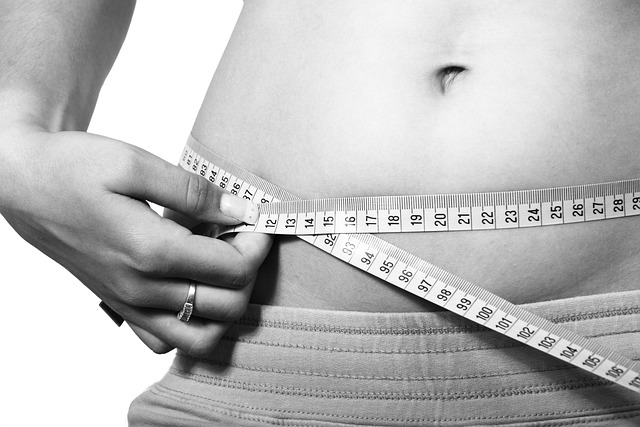 Person measuring waist with a flexible tape measure
